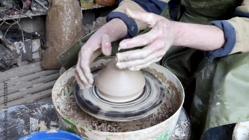 Hands of a potter on a pottery wheel close-up. Old traditional art, handmade, clay and ceramic production. Pottery workshop in subdued soft light Hands of a potter on a pottery wheel close-up. Old traditional art, handmade, clay and ceramic production. Pottery workshop in subdued soft light