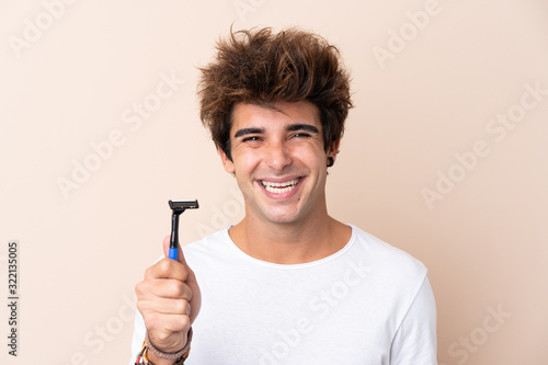Young handsome man shaving his beard smiling a lot