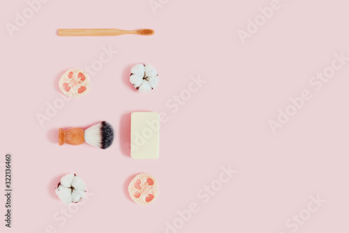 Zero waste concept. Natural bamboo toothbrush, natural sponge, cotton flowers, shaving brush on pink background. Flat lay, top view, copy space.