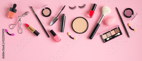 Frame top border of makeup products and cosmetics on pastel pink background. Flat lay, top view. Beauty blog banner template. Female make-up concept