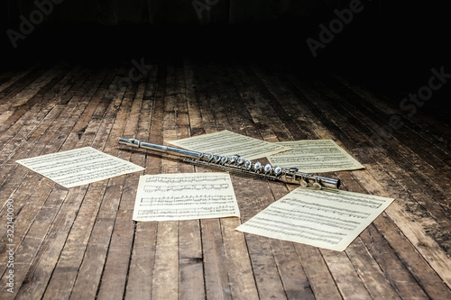 flute lies on a wooden stage among sheet music with notes photo