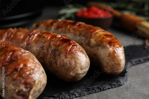 Tasty grilled sausages on grey table, closeup