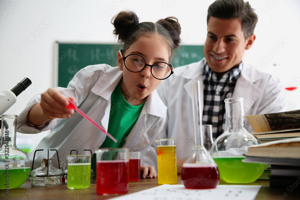 Teacher with pupil making experiment at table in chemistry class Teacher with pupil making experiment at table in chemistry class