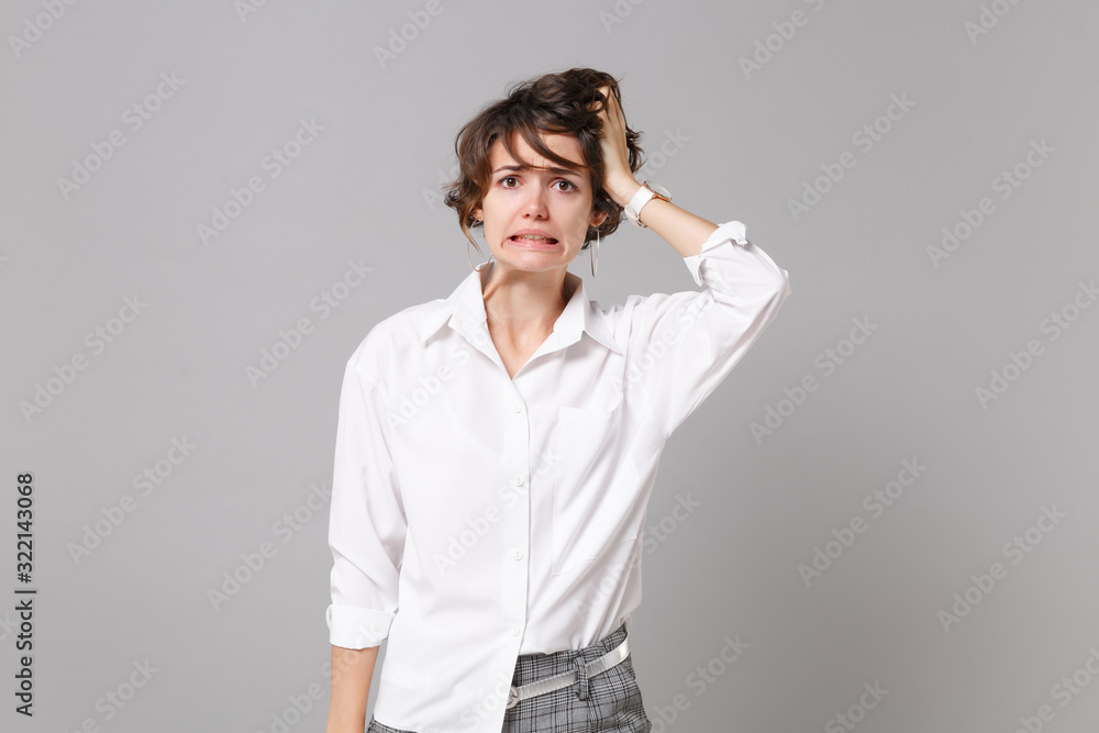 Confused puzzled young business woman in white shirt posing isolated on grey wall background studio portrait. Achievement career wealth business concept. Mock up copy space. Putting hand on head. Confused puzzled young business woman in white shirt posing isolated on grey wall background studio portrait. Achievement career wealth business concept. Mock up copy space. Putting hand on head.