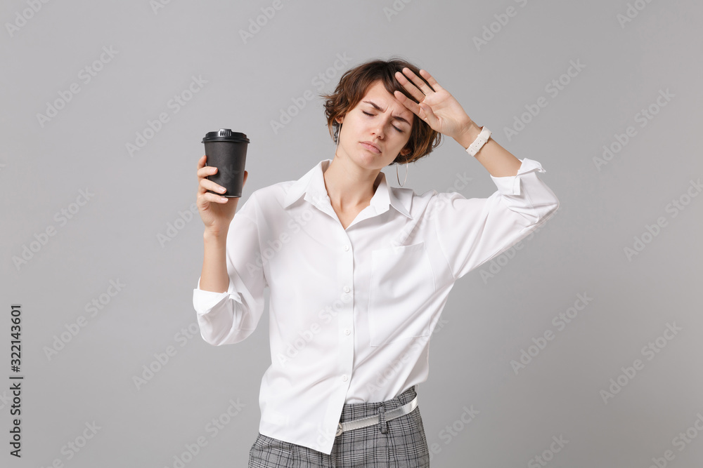 Tired young business woman in white shirt posing isolated on grey background. Achievement career wealth business concept. Mock up copy space. Holding paper cup of coffee or tea, keeping eyes closed. Tired young business woman in white shirt posing isolated on grey background. Achievement career wealth business concept. Mock up copy space. Holding paper cup of coffee or tea, keeping eyes closed.