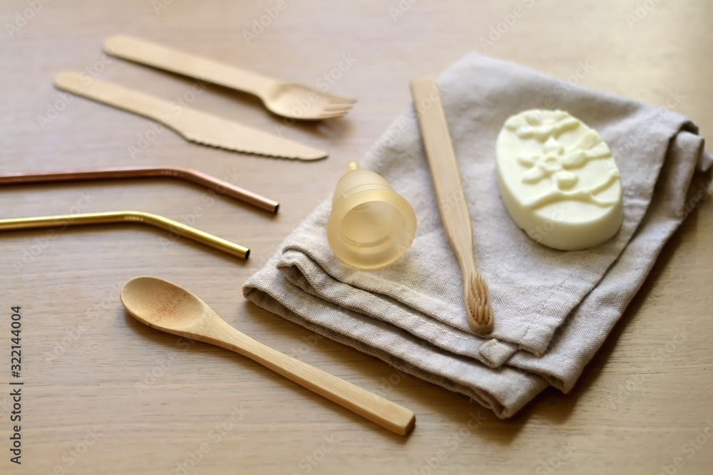Various zero waste products on a wooden table: cloth, soap, cutlery, straws, toothbrush and menstrual cup. Various zero waste products on a wooden table: cloth, soap, cutlery, straws, toothbrush and menstrual cup.