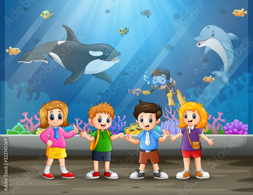 Funny school children looking at fish in aquarium