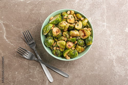 Delicious roasted brussels sprouts with peanuts on grey marble table, flat lay