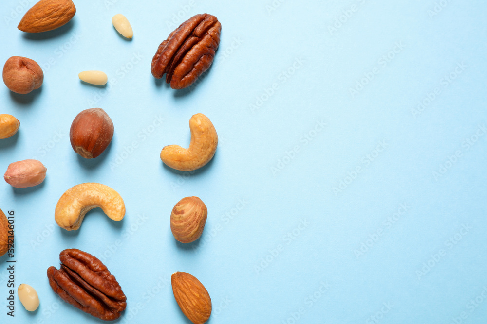 Different delicious nuts on light blue background, flat lay. Space for text Different delicious nuts on light blue background, flat lay. Space for text