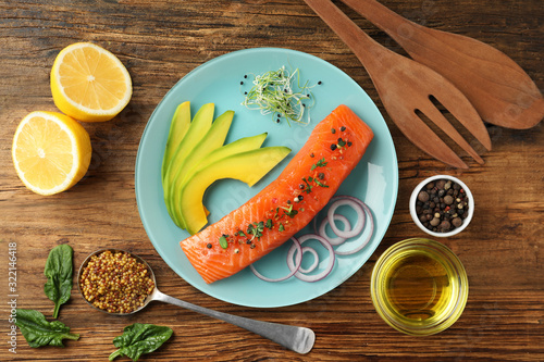 Delicious salmon with spinach and avocado served on wooden table, flat lay