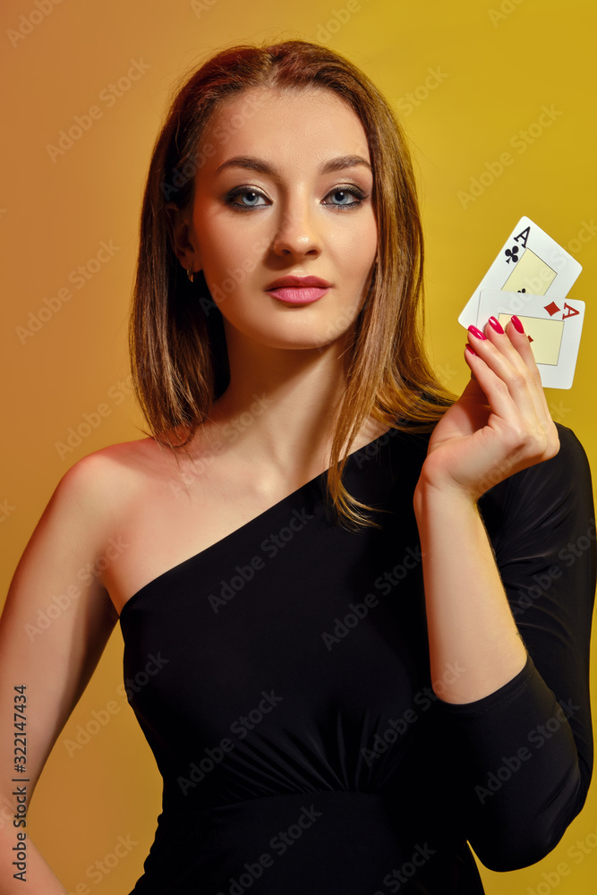 Blonde woman with bright make-up, in black dress is showing two aces, posing against colorful background. Gambling, poker, casino. Close-up. Blonde woman with bright make-up, in black dress is showing two aces, posing against colorful background. Gambling, poker, casino. Close-up.
