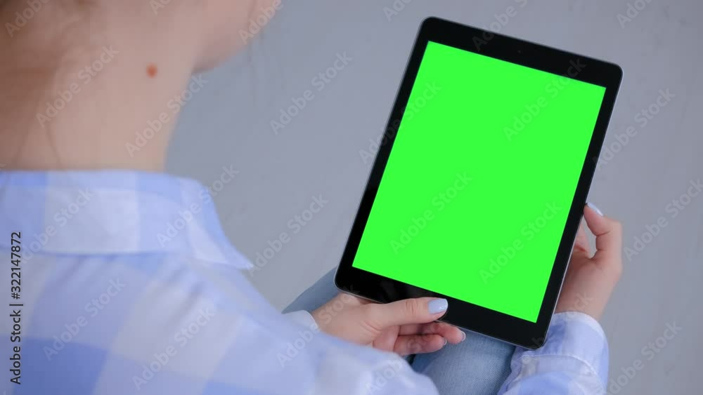 Woman sitting on floor and looking at black tablet computer device with blank green display. Mock up, entertainment, copyspace, freelance, template, leisure time, green screen, technology concept Woman sitting on floor and looking at black tablet computer device with blank green display. Mock up, entertainment, copyspace, freelance, template, leisure time, green screen, technology concept