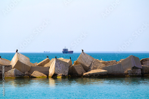 Seagulls on square stones in a turquoise sea and a ship on the background photo