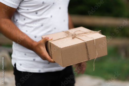 Close-up of man holding gift box with small bow. Unrecognizable successful man presenting Valentines gift. Gift-giving concept. Surprising her.. © MONIUK ANDRII