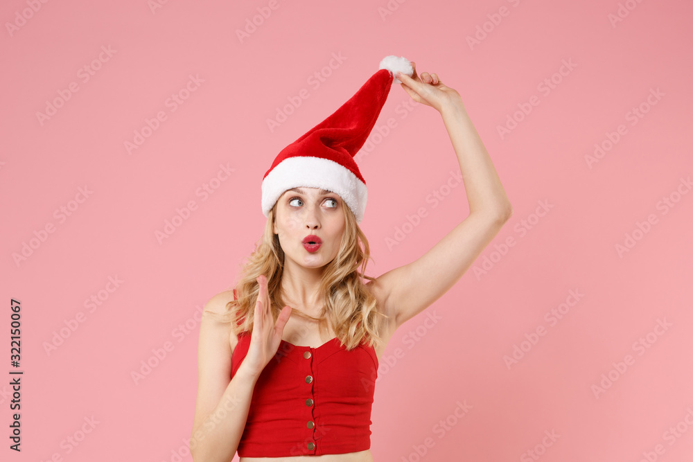 Amazed young woman in red sexy clothes, Christmas hat isolated on pastel pink wall background studio portrait. Happy New Year 2020 celebration holiday concept. Mock up copy space. Looking up aside. Amazed young woman in red sexy clothes, Christmas hat isolated on pastel pink wall background studio portrait. Happy New Year 2020 celebration holiday concept. Mock up copy space. Looking up aside.