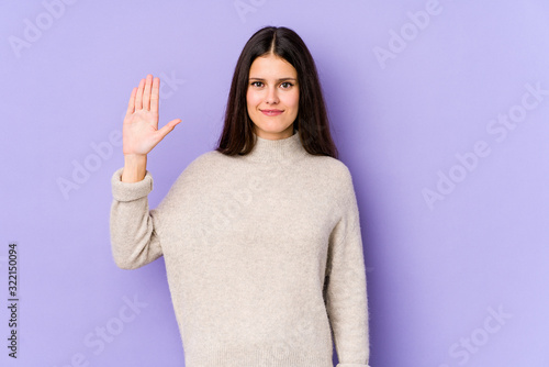 Young caucasian woman isolated on purple background smiling cheerful showing number five with fingers.