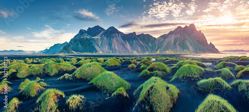 Panoramic view from flying drone of black sand dunes on Stokksnes cape with Vestrahorn (Batman Mountain) on background. Impressive sunrise in Iceland, Europe. Beauty of nature concept background.. © Andrew Mayovskyy