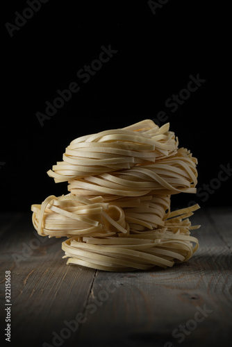 raw egg noodles stacked on wood closeup photo