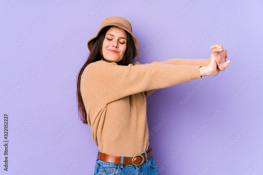 Young caucasian woman isolated on purple background stretching arms, relaxed position. Young caucasian woman isolated on purple background stretching arms, relaxed position.