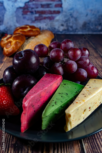 Different Dutch cheese types on plate and bread and fruit in the background