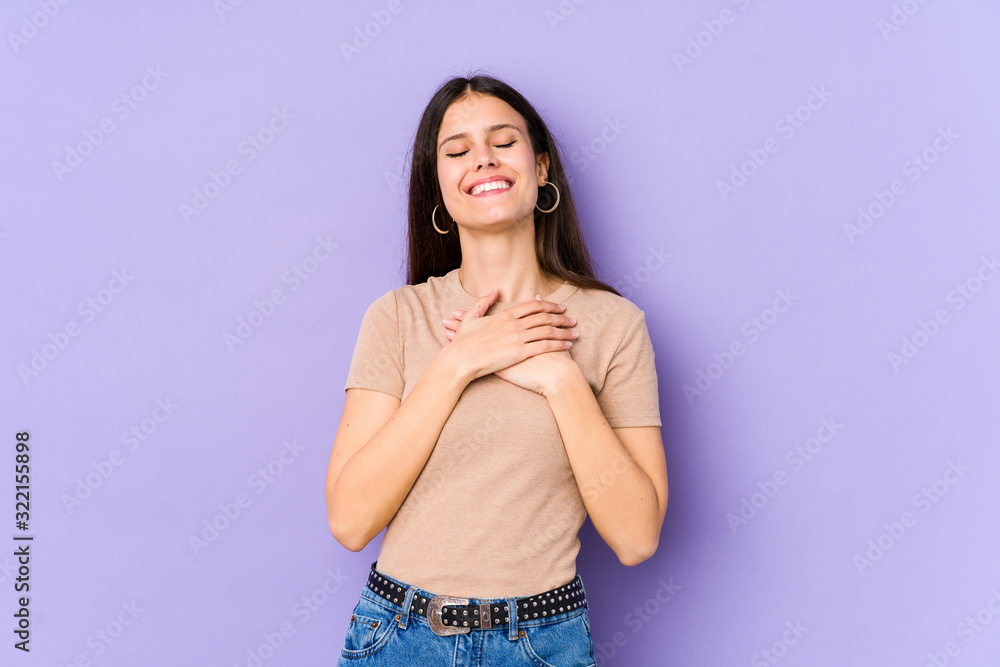 Young caucasian woman isolated on purple background laughing keeping hands on heart, concept of happiness. Young caucasian woman isolated on purple background laughing keeping hands on heart, concept of happiness.