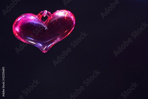 Colorful plastic heart photographed on mirror surface in studio