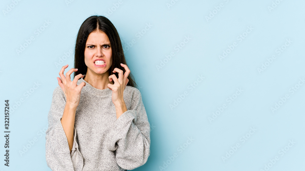 Young caucasian woman isolated on blue background upset screaming with tense hands. Young caucasian woman isolated on blue background upset screaming with tense hands.