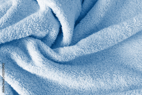 Fluffy classic blue towel background, close-up. Gentle baby pastel fabric with waves and folds. Folded tender light blue towel texture. Bath fluffy towel, spa background photo