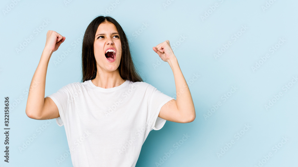 Young caucasian woman isolated on blue background raising fist after a victory, winner concept. Young caucasian woman isolated on blue background raising fist after a victory, winner concept.