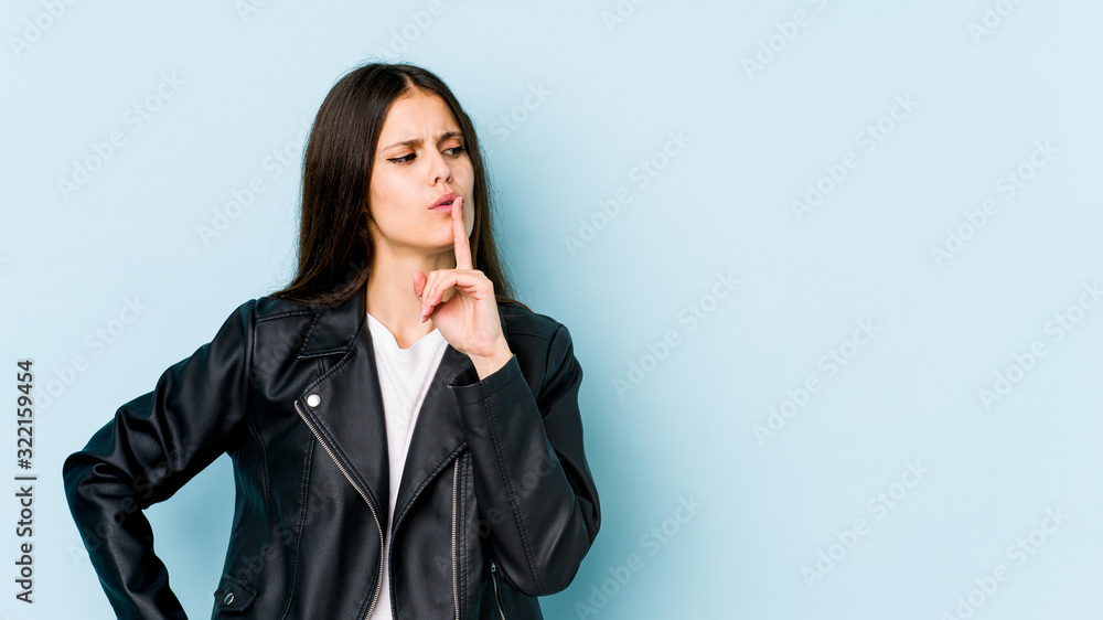Young caucasian woman isolated on blue background keeping a secret or asking for silence. Young caucasian woman isolated on blue background keeping a secret or asking for silence.