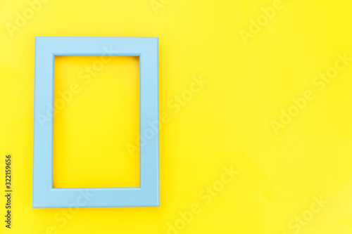 Simply design with empty blue frame isolated on yellow colourful trendy background. Top view, flat lay, copy space, mock up. Minimal concept.
