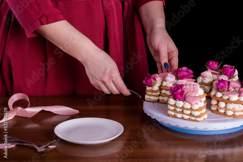 The hands of the confectioner with a delicate and delicious cake of letters. Cake with live flowers, white chocolate, beas. Hands of a pastry chef, packing dessert.