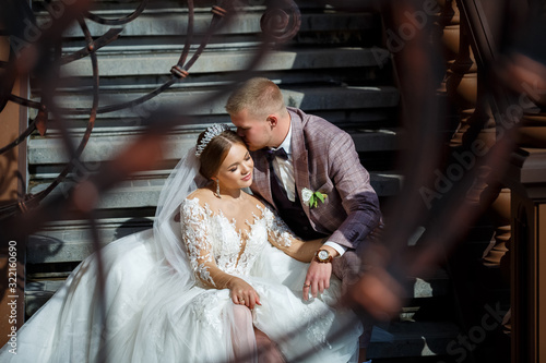 Bride in white dress and groom in costumes hug on the steps