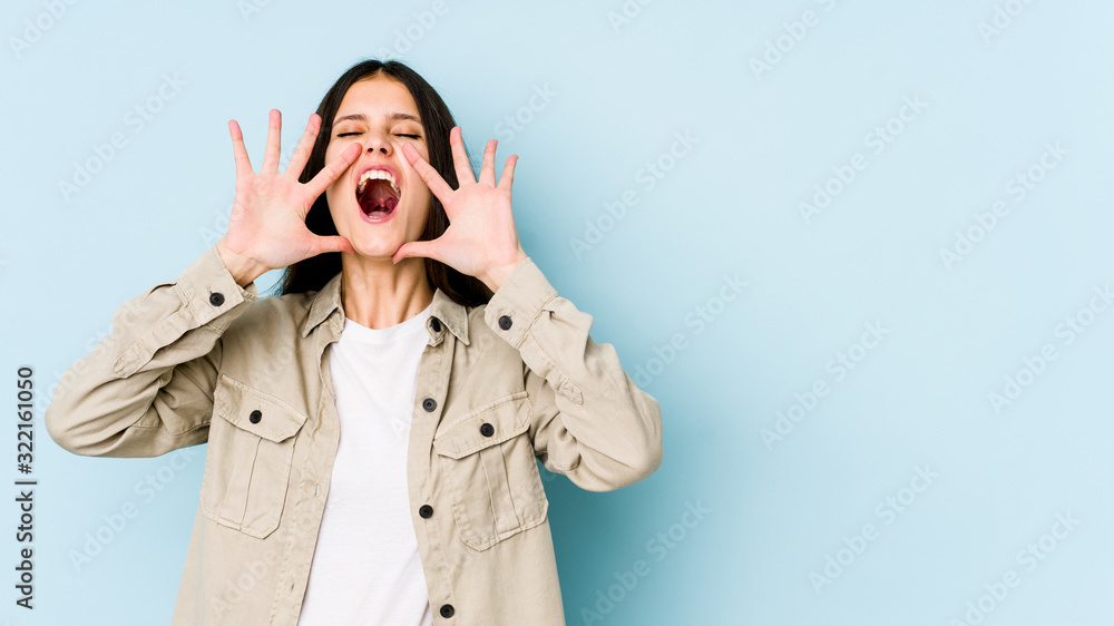 Young caucasian woman isolated on blue background shouting excited to front. Young caucasian woman isolated on blue background shouting excited to front.