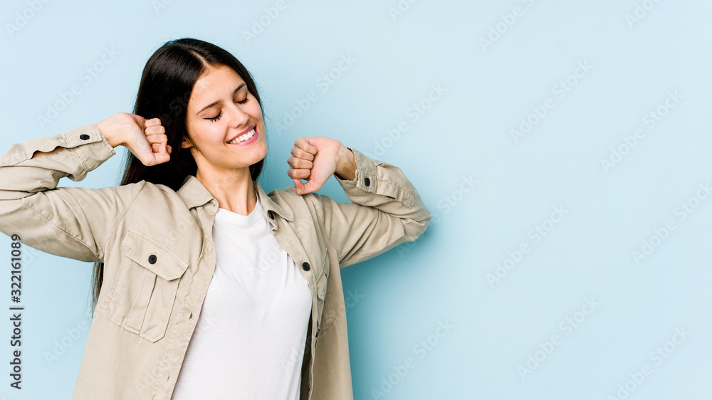 Young caucasian woman isolated on blue background stretching arms, relaxed position. Young caucasian woman isolated on blue background stretching arms, relaxed position.