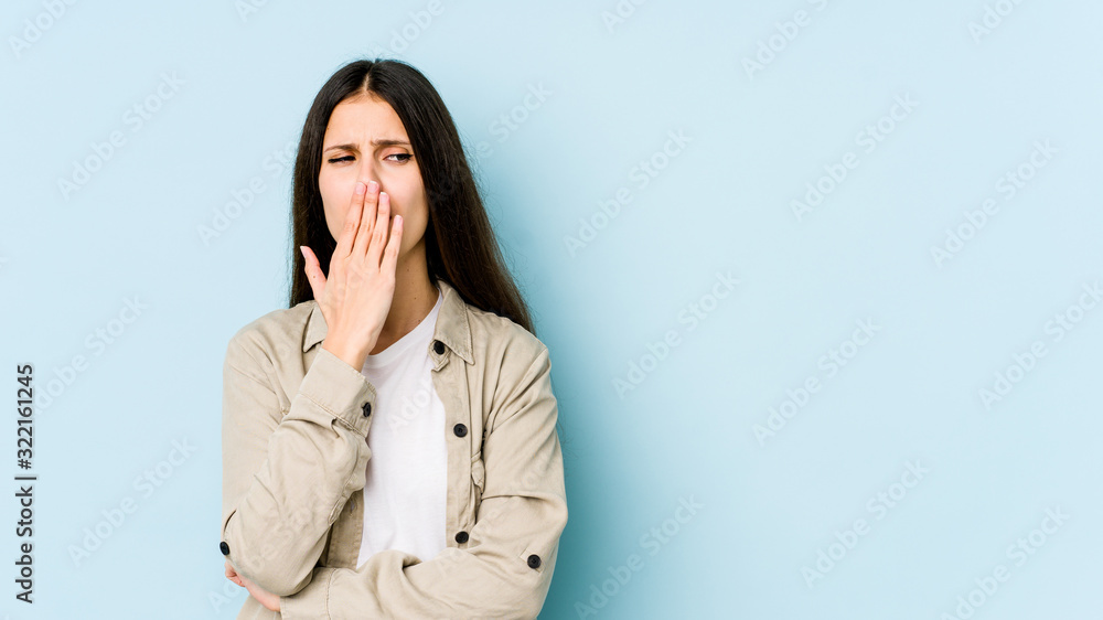 Young caucasian woman isolated on blue background yawning showing a tired gesture covering mouth with hand. Young caucasian woman isolated on blue background yawning showing a tired gesture covering mouth with hand.