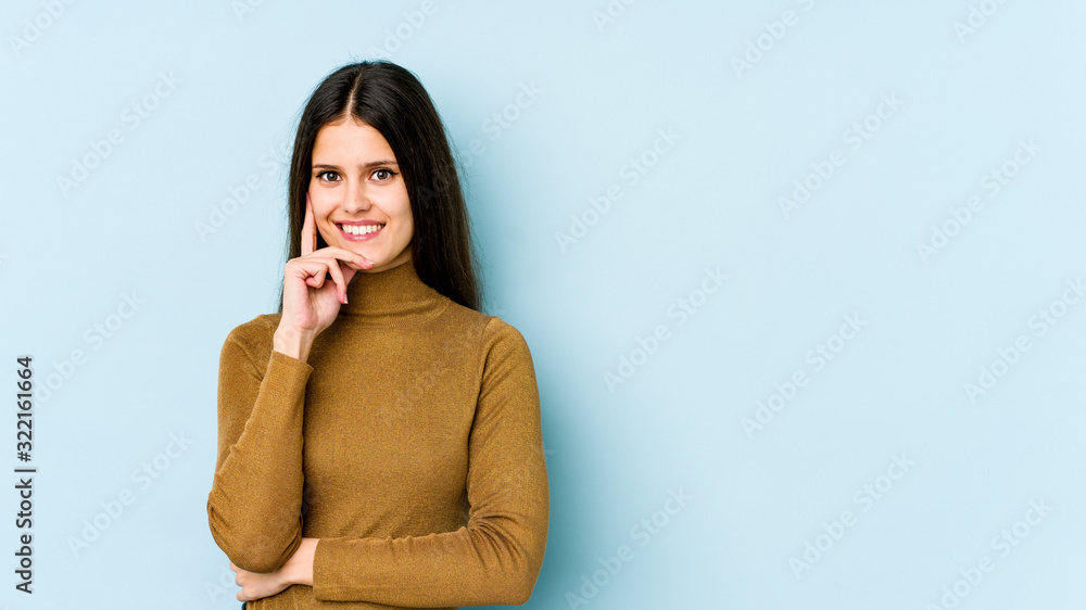 Young caucasian woman isolated on blue background smiling happy and confident, touching chin with hand. Young caucasian woman isolated on blue background smiling happy and confident, touching chin with hand.