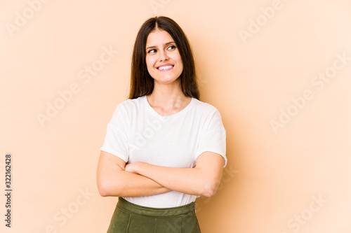Young caucasian woman isolated on beige background smiling confident with crossed arms.