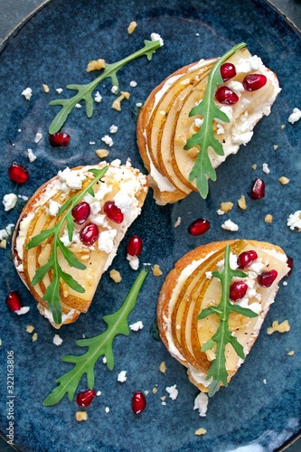 Crostini with pear, feta cheese, honey, nuts and pomegranate. Top view with copy space.