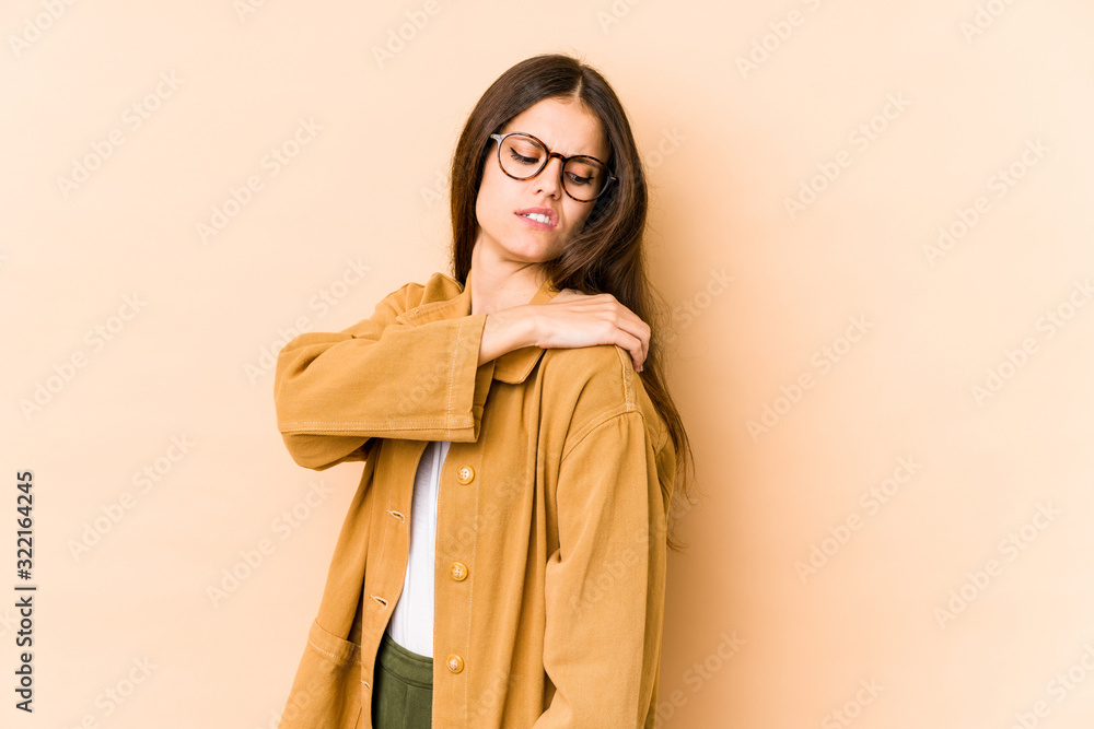 Young caucasian woman isolated on beige background having a shoulder pain.