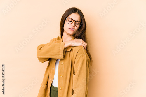 Young caucasian woman isolated on beige background having a shoulder pain. © Asier