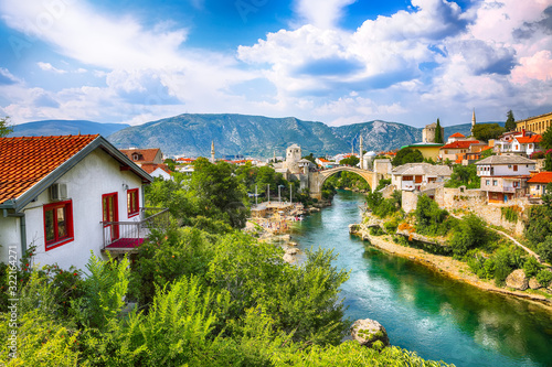 Fantastic Skyline of Mostar with the Mostar Bridge, houses and minarets, during sunny day.