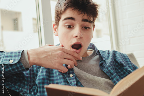Canvas Print young teenage boy reading or studying at home