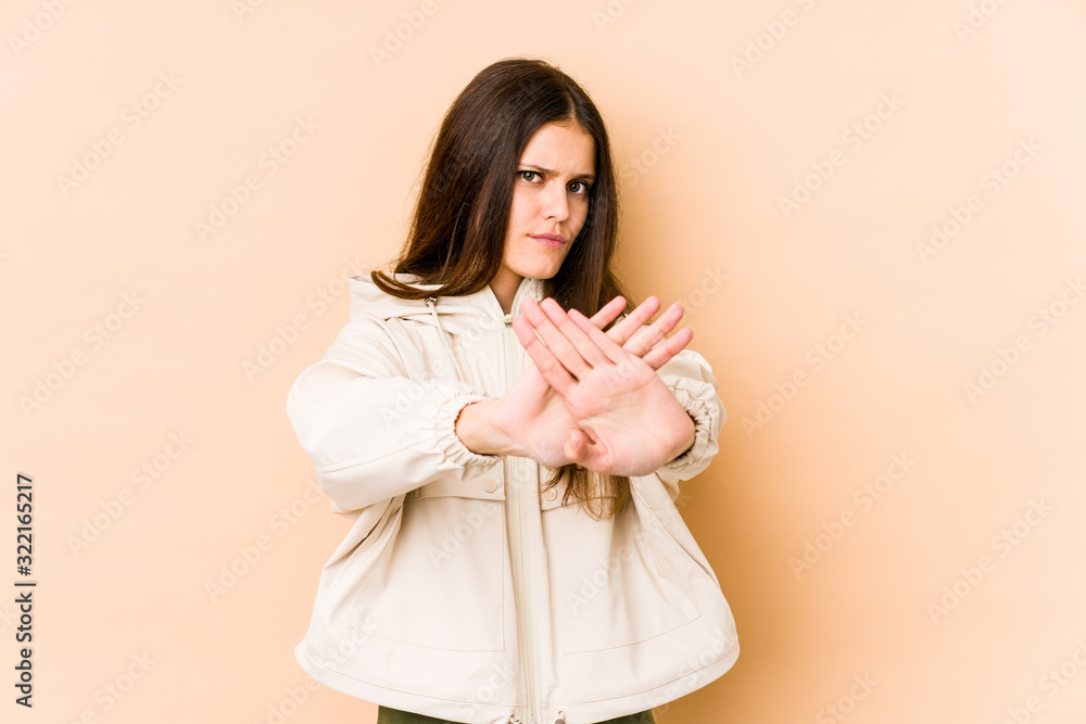 Young caucasian woman isolated on beige background standing with outstretched hand showing stop sign, preventing you. Young caucasian woman isolated on beige background standing with outstretched hand showing stop sign, preventing you.