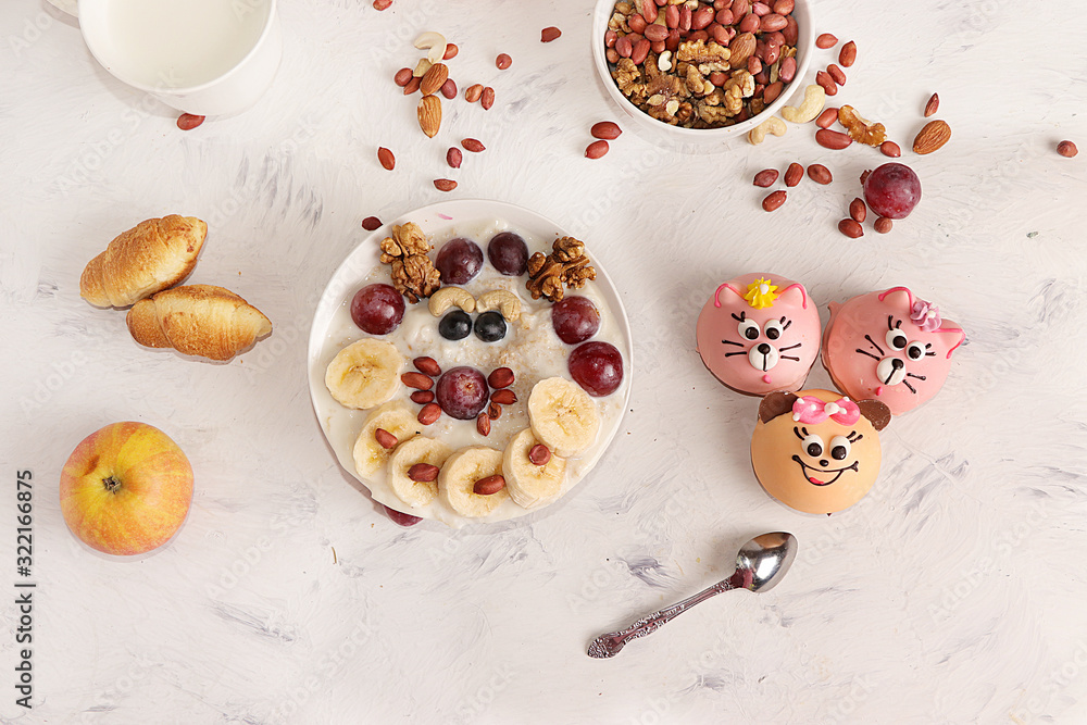 Healthy breakfast, fun food for children. The concept of healthy and natural food. Oatmeal with granola or granola, grapes, nuts and croissants, top view, selective focus. Healthy breakfast, fun food for children. The concept of healthy and natural food. Oatmeal with granola or granola, grapes, nuts and croissants, top view, selective focus.