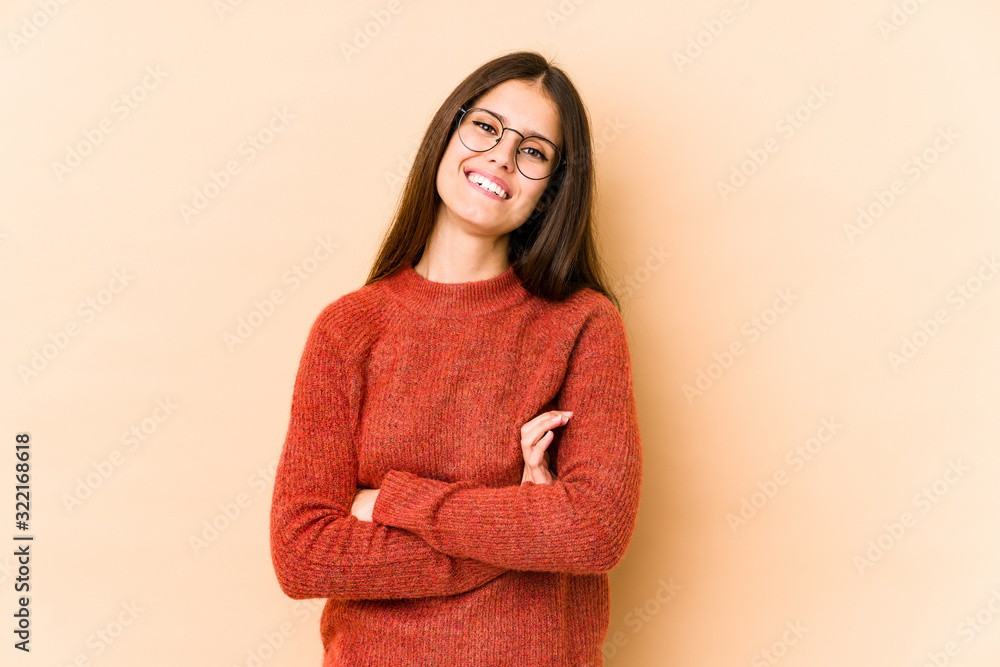 Fototapeta premium Young caucasian woman isolated on beige background who feels confident, crossing arms with determination.