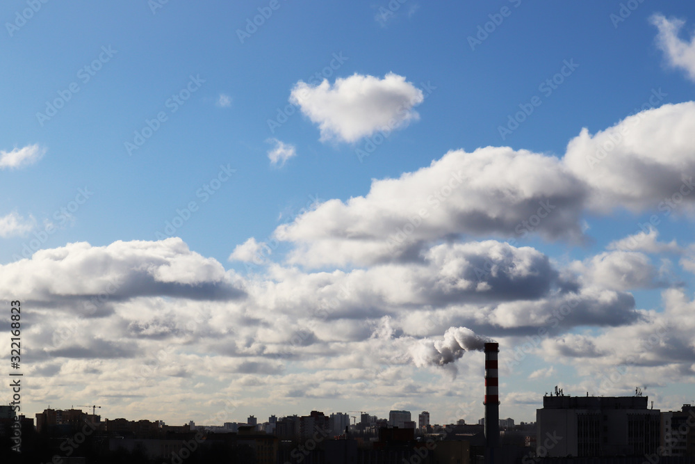 A factory chimney emits clouds of smoke that are mixed with ordinary clouds. The theme of ecology and nature. A factory chimney emits clouds of smoke that are mixed with ordinary clouds. The theme of ecology and nature.