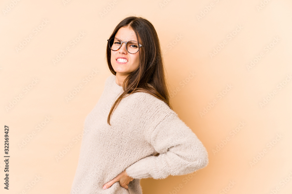 Young caucasian woman isolated on beige background suffering a back pain.