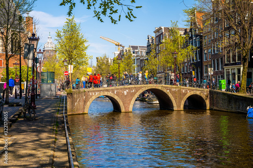 Photography Stunning view of Amsterdam canals and typical dutch houses with narrow cosy streets filled with bicycles in the capital of Netherlands, Europe on a beautiful sunny day