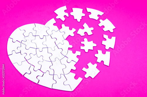 Φωτογραφία Heart rendered into white puzzle pieces on pink background